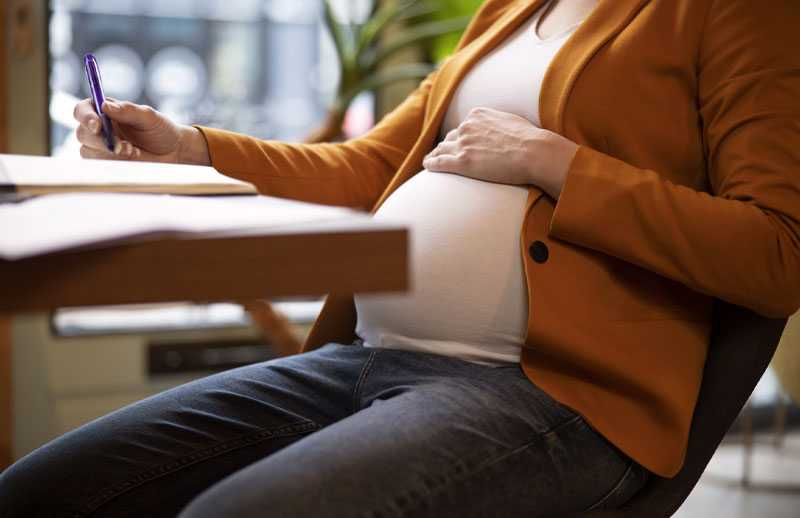 Pregnant woman writing notes during a consultation
